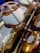 Close-up view of a brass instrument with detailed focus on the mechanism and keys, revealing polished, reflective surfaces with some signs of wear. The intricate parts are captured in warm lighting, highlighting the metallic texture.