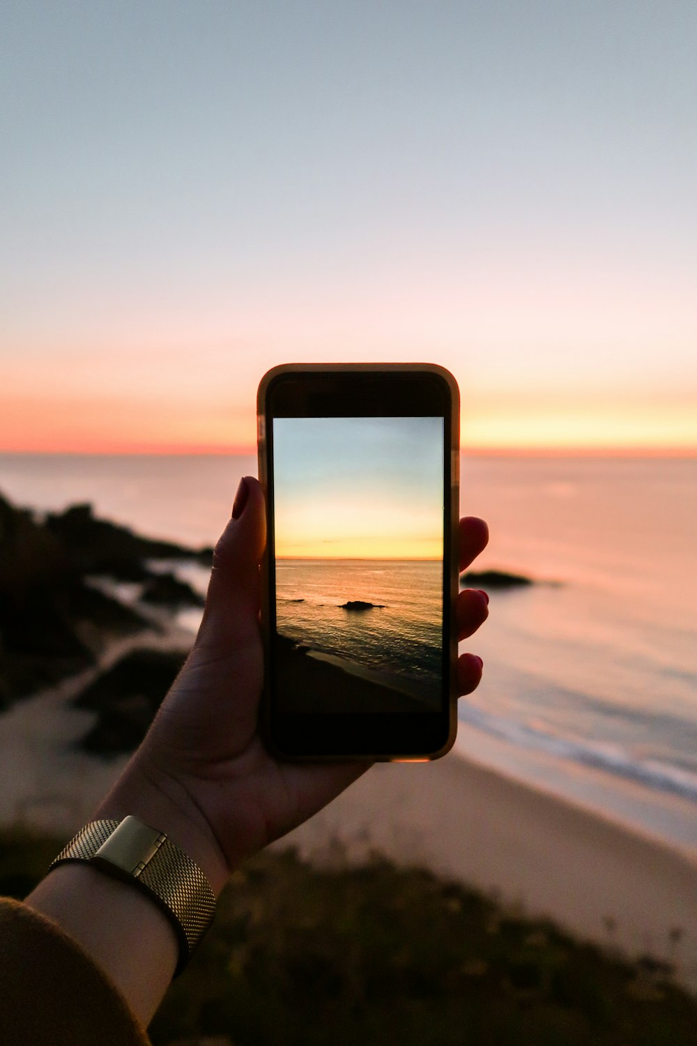 person holding smartphone taking photo of sea