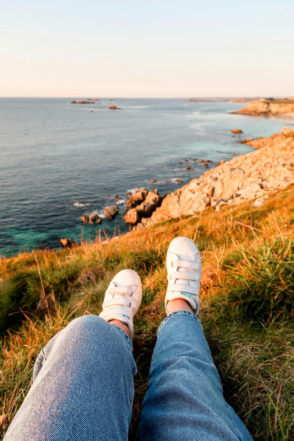 person sitting on cliff near body of water