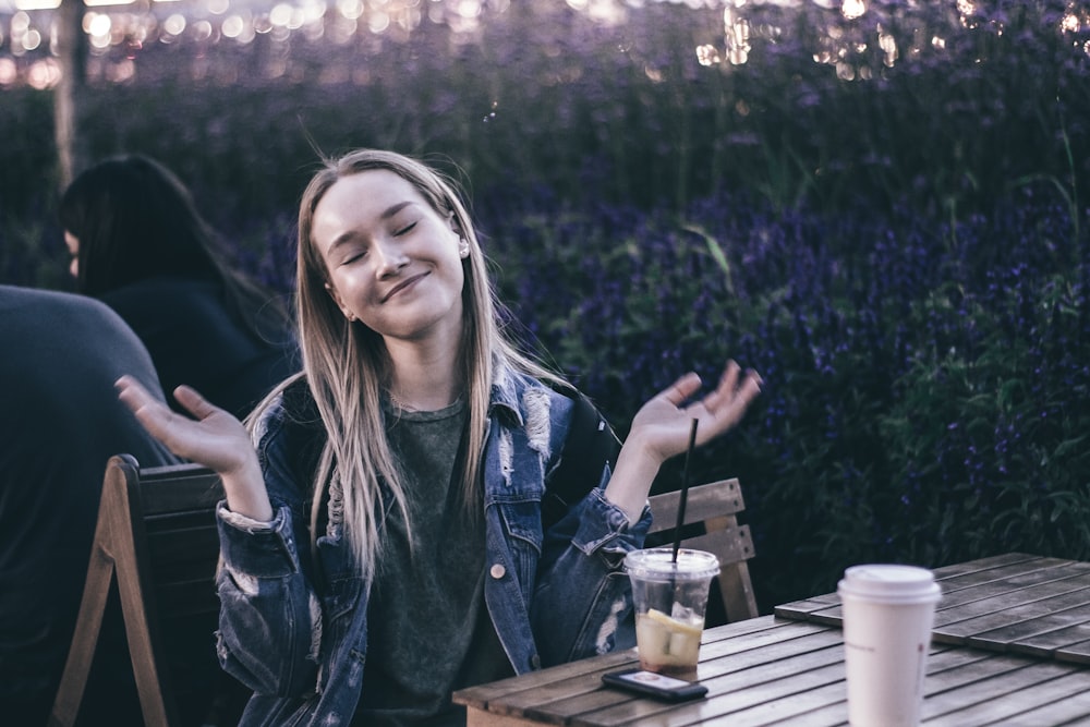 woman in denim jacket sitting in front of slatted table