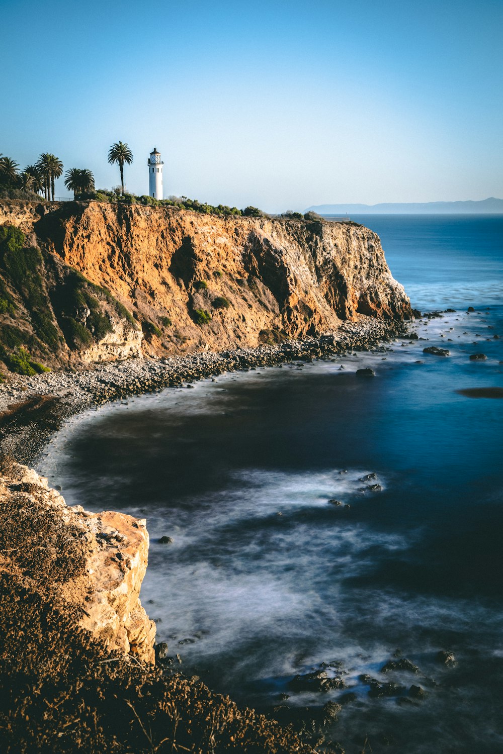 white lighthouse on sea cliff during daytime