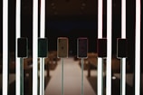 Several smartphones are displayed on stands, illuminated by vertical, glowing light bars. The setting appears to be a modern, dimly lit environment possibly in a retail or exhibition space.