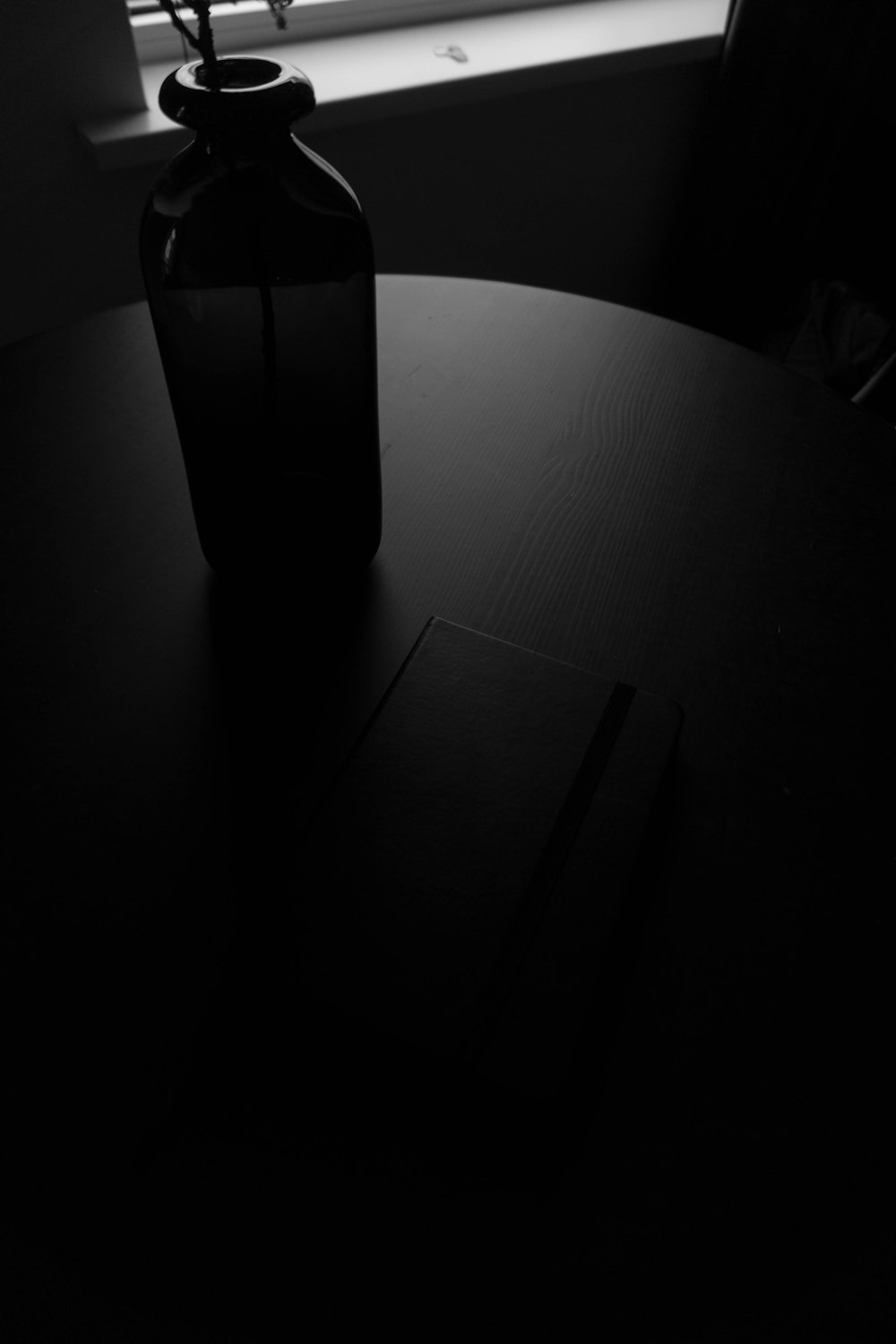 grayscale photography of bottle on table