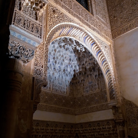 Intricate architectural details with elaborate patterns and carvings adorn a stone archway. The design features geometric and arabesque motifs, highlighting traditional craftsmanship.