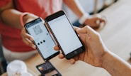 two person's hands holding turned-on phones