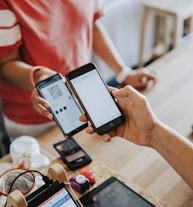 two person's hands holding turned-on phones