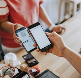 two person's hands holding turned-on phones