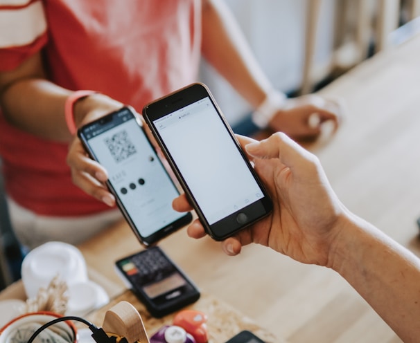 two person's hands holding turned-on phones