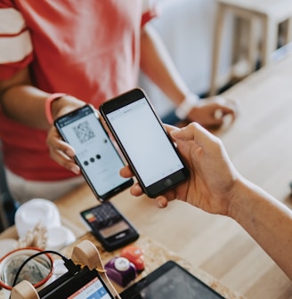 two person's hands holding turned-on phones