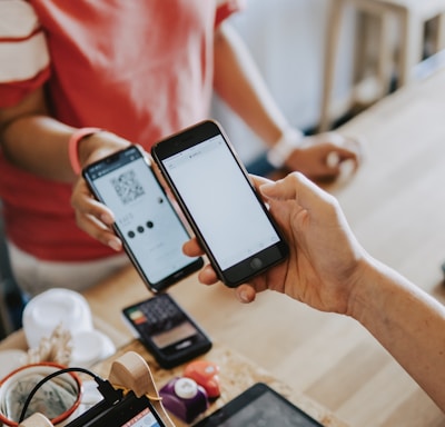 two person's hands holding turned-on phones