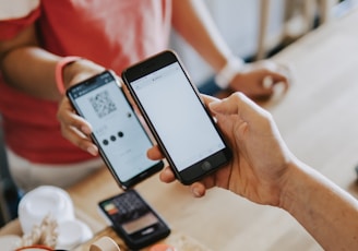 two person's hands holding turned-on phones