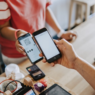 two person's hands holding turned-on phones