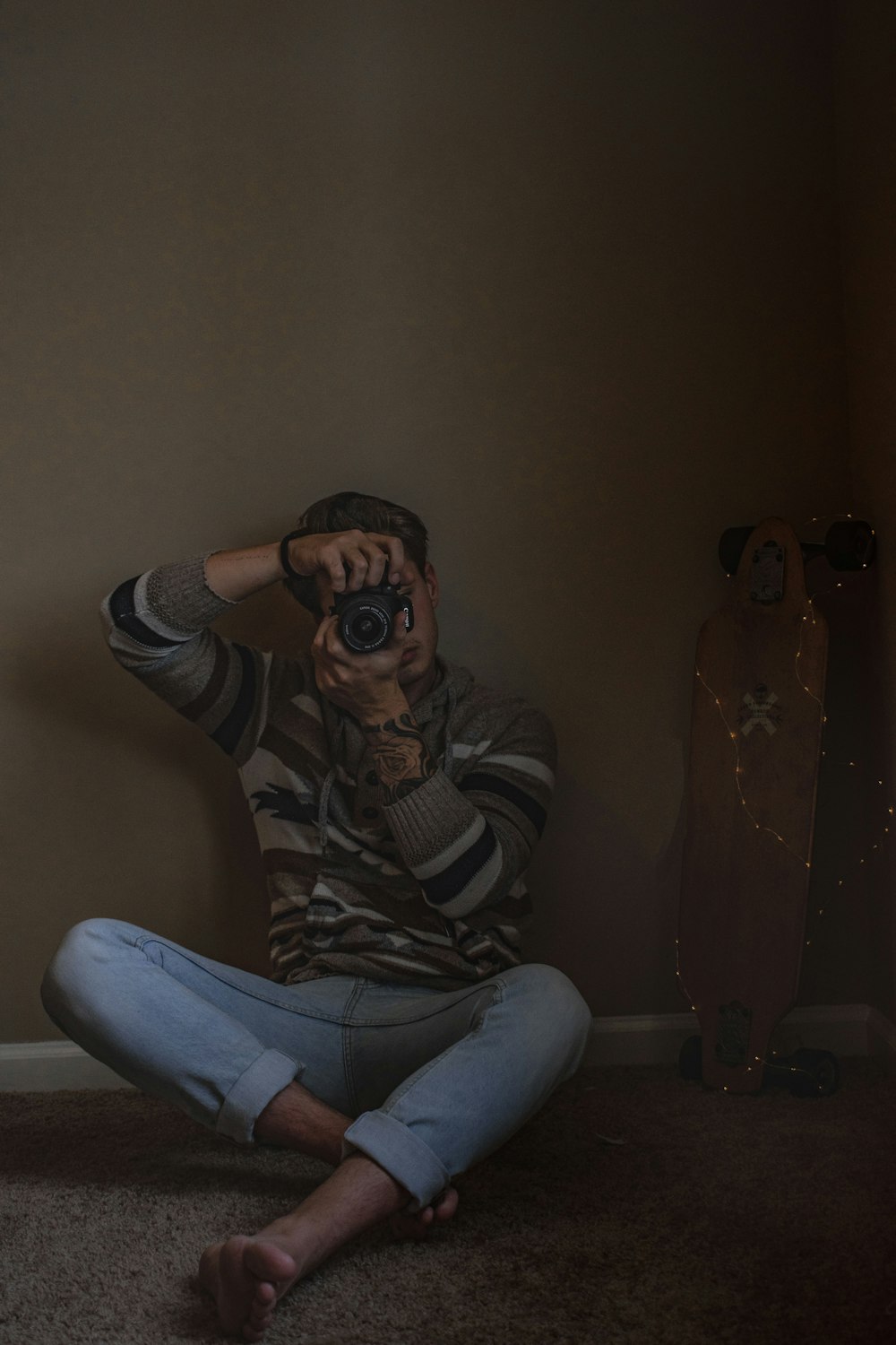 man wearing grey and white striped sweater sitting on floor taking picture