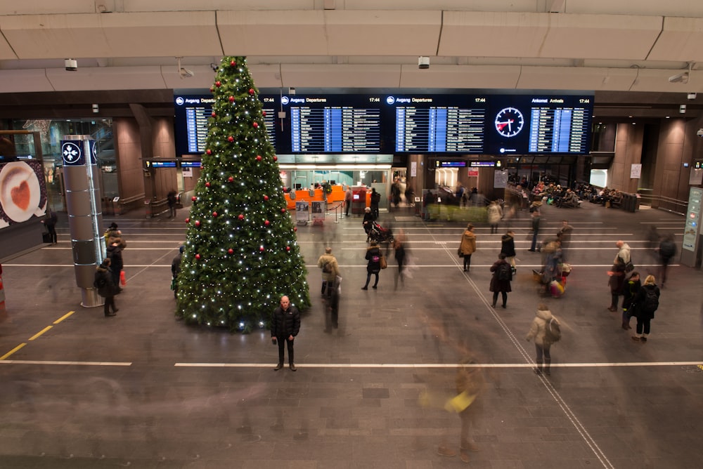 group of people inside building with Christmas tree