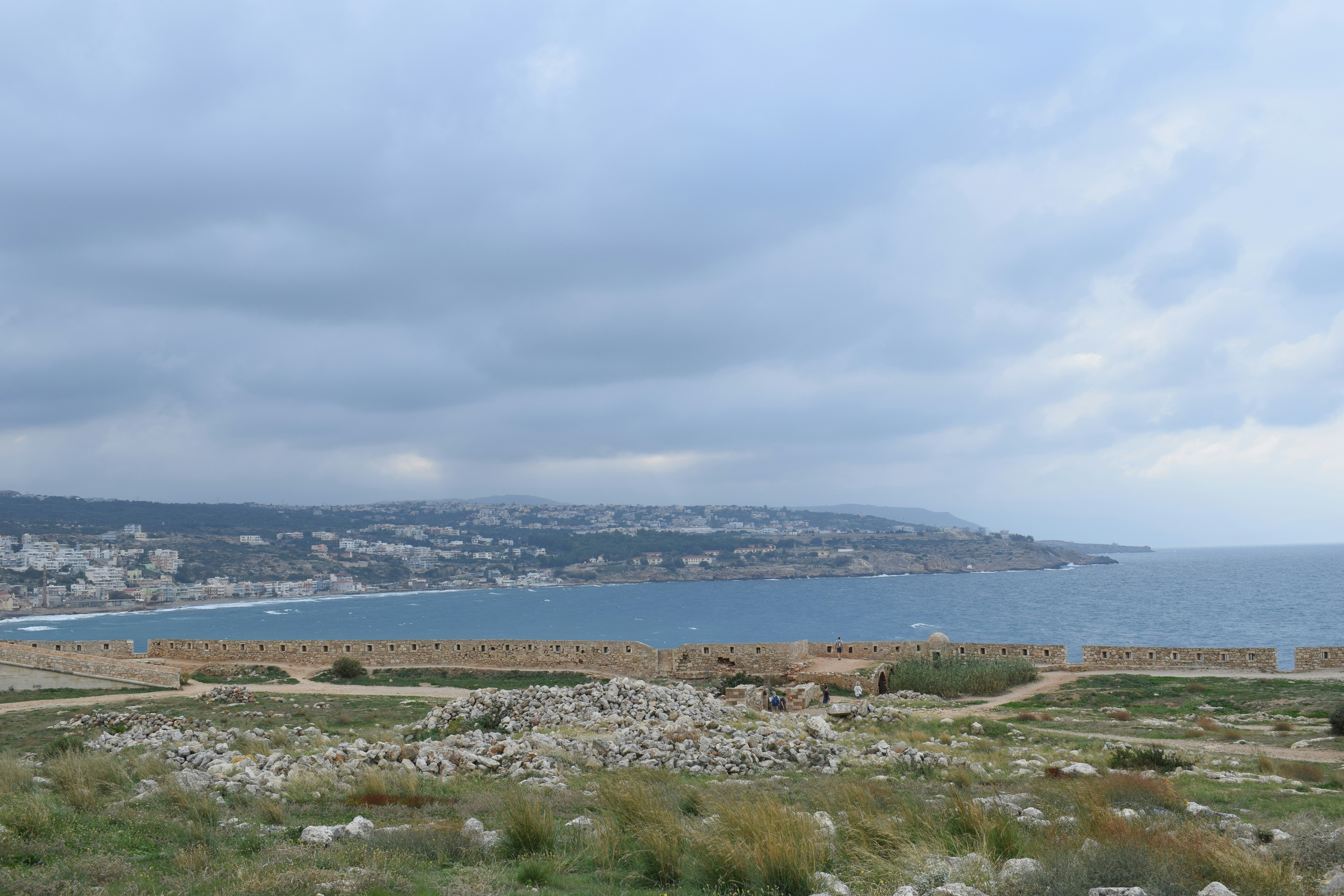 aerial photography of houses on green field viewing mountain and sea under blue and white sky during daytime
