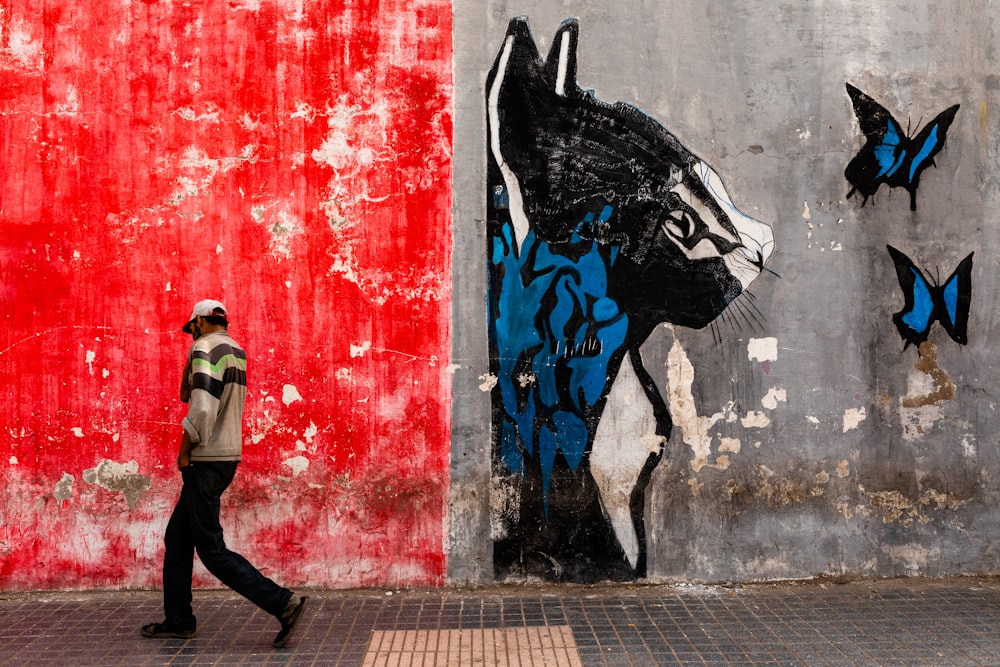 man walking on the street with graffiti on wall