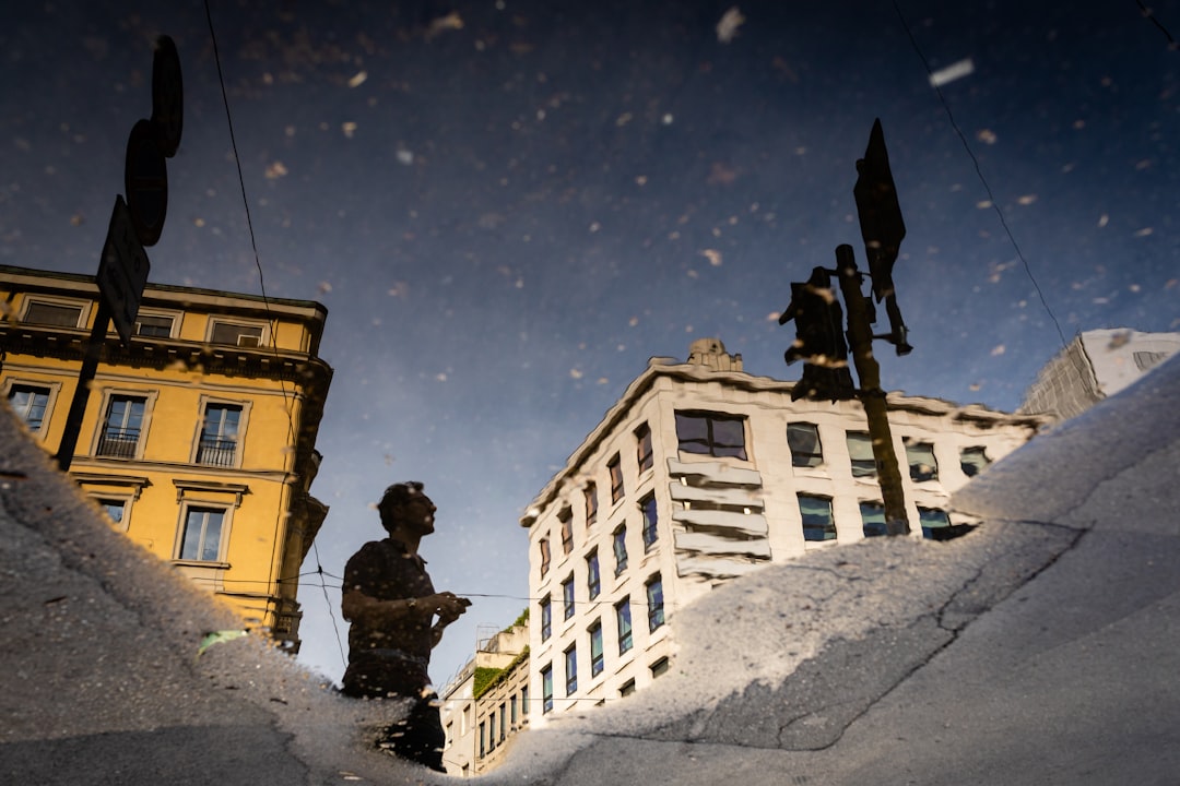 man reflection on water near traffic light