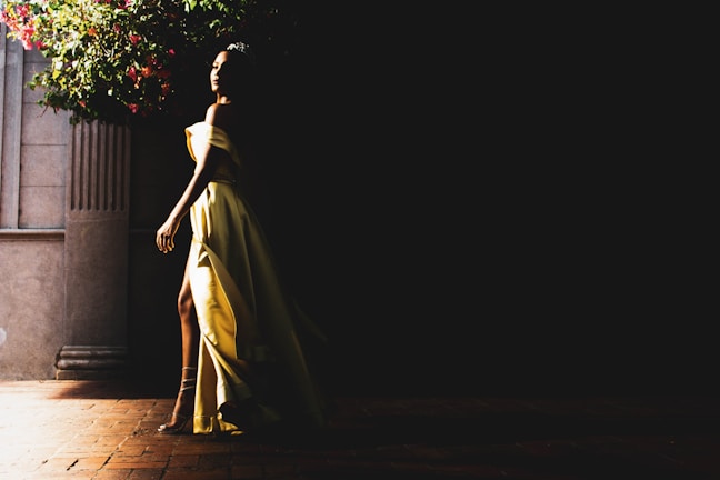 Elegant woman in a flowing dress walking through a sunlit urban street at golden hour