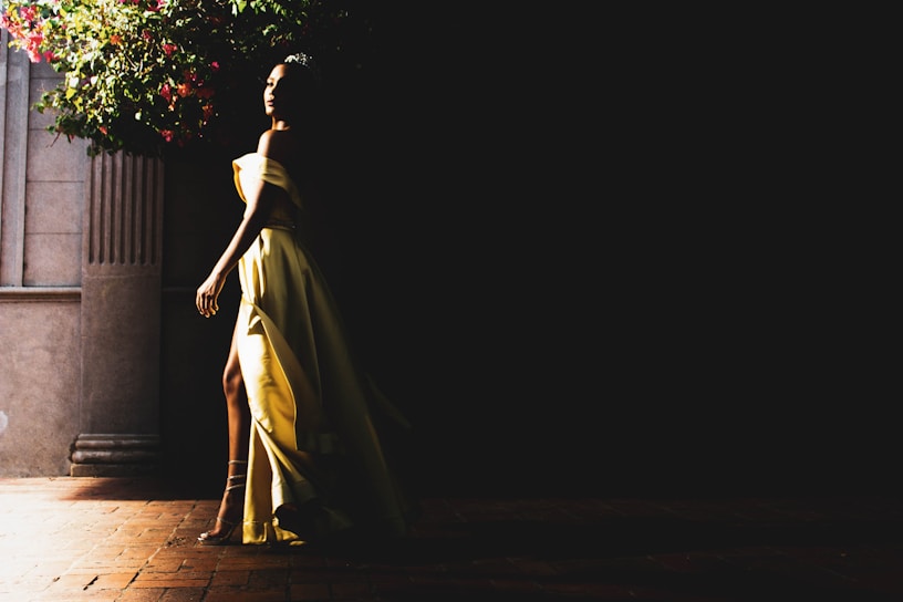 Elegant woman in a flowing rose gold dress walking through a sunlit Parisian street.