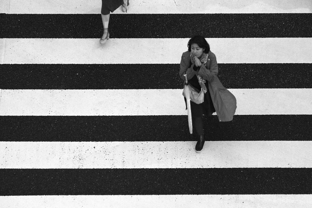 woman in gray coat walking on crosswalk