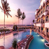 An elegant resort pool area with warm lighting and forest views as the sun sets.
