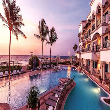 An elegant resort poolside with sleek architecture framed by lush greenery under a warm sunset glow.