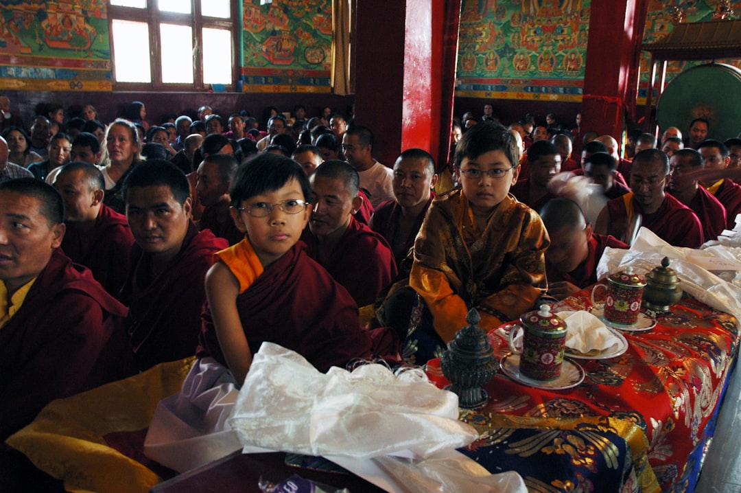 Spiritual adepts, cousins - Asanga Sakya, Abhaya Sakya, children, seated near their grandfather, HH Dagchen Sakya (not shown), tea cups, vessels holding rice offerings, white silk offering katas, silk table covers, Tibetan Buddhist lamas, monks, Eastern / Western students, wall murals, green drum, Tharlam Monastery, Boudha, Kathmandu, Nepal  This is a blessed image. Please, If printed do not place on the floor, do not step over or on, after use please burn.