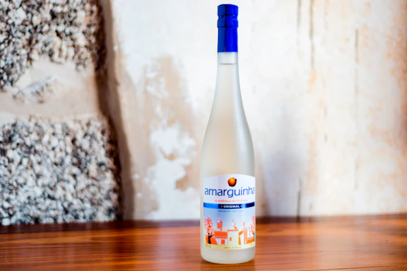 A rustic bottle of artisanal pisco with grapes and a wooden background.