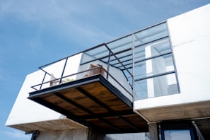 Architectural detail of a cantilevered balcony with black steel framing against a white facade