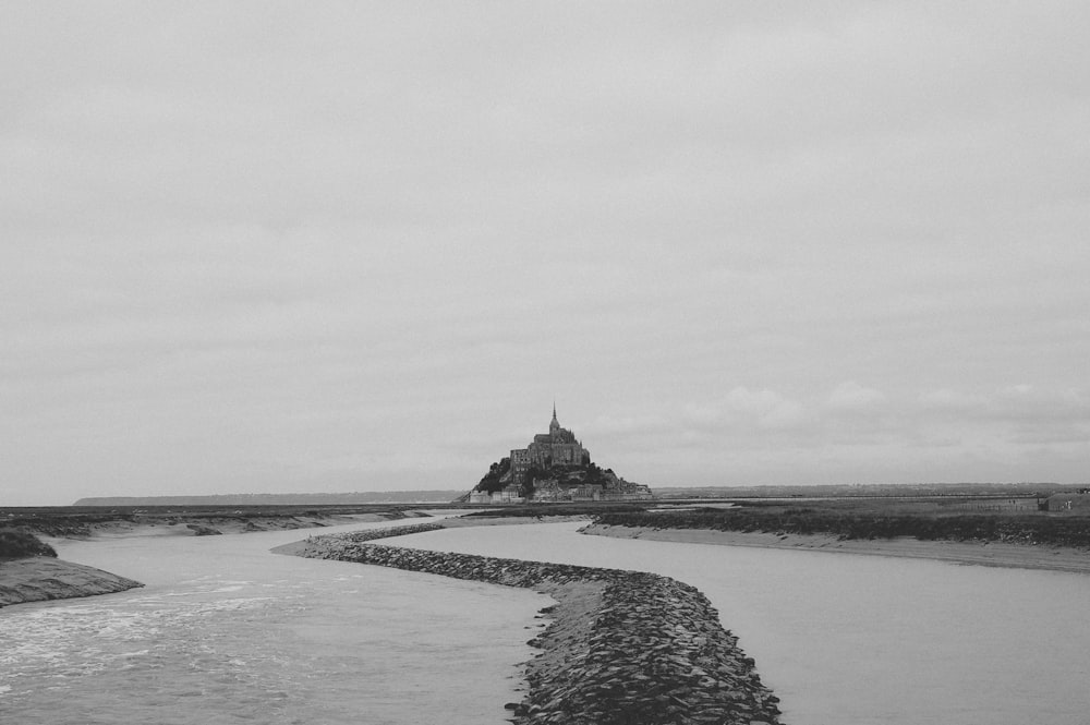 a black and white photo of a river with a castle in the background