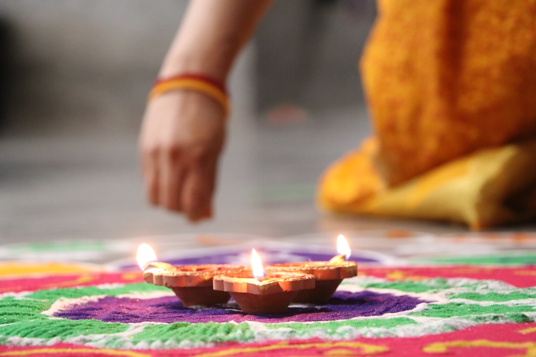 woman creates intricate sand drawing around a candles during Diwali. 