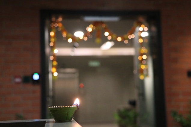 A softly lit temple entrance glowing with warm diya lamps against a twilight sky.