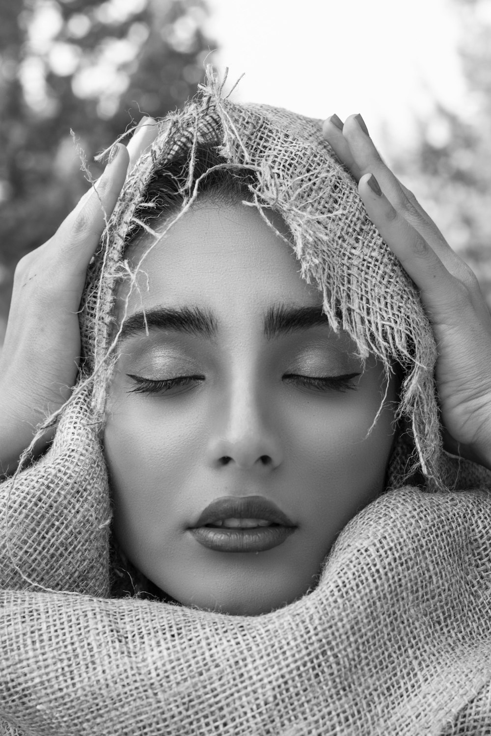 grayscale photo of woman covering head with burlap