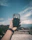 Close-up of a hand holding a phone with a clear acrylic case reflecting sunlight.