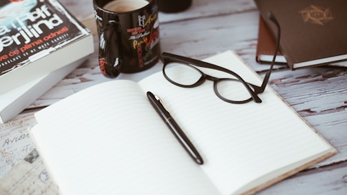 An open notebook with colorful pens and a coffee cup.