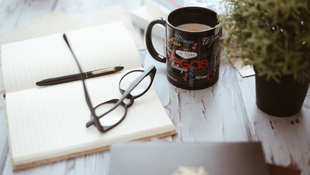 black ceramic mug beside notebook