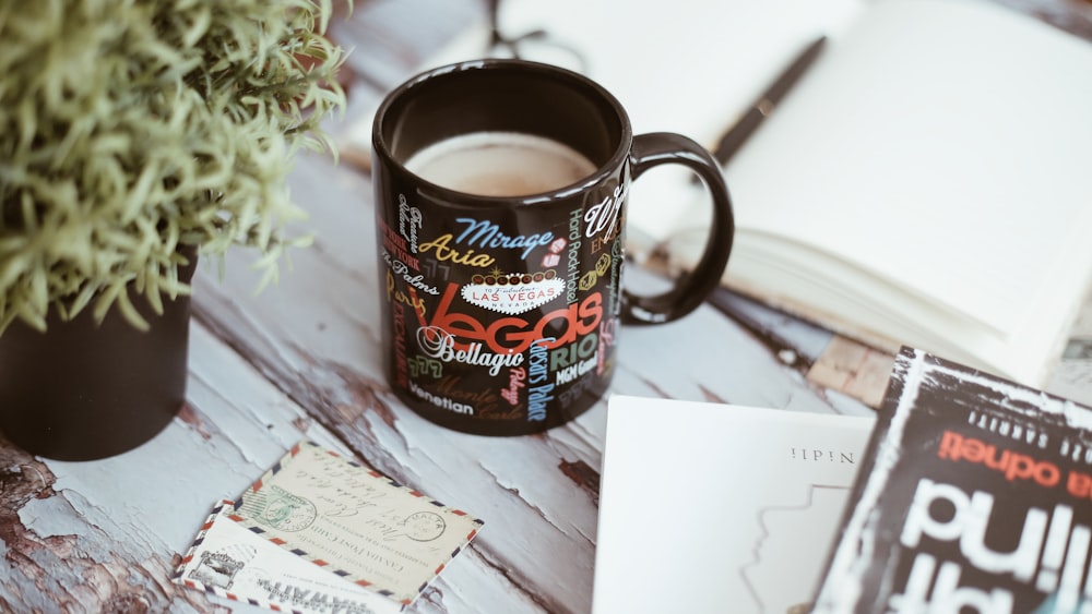 black ceramic mug beside notebook