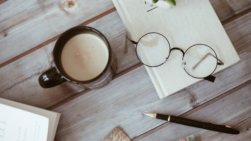 a cup of coffee near pen and eyeglasses