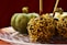 A close-up of a beautifully presented caramel apple on a rustic wood table.