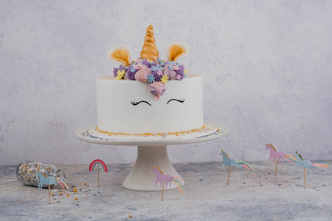 unicorn cake on stand beside wall