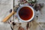 Close-up of a steaming cup of tea on a rustic wooden table with snacks nearby.