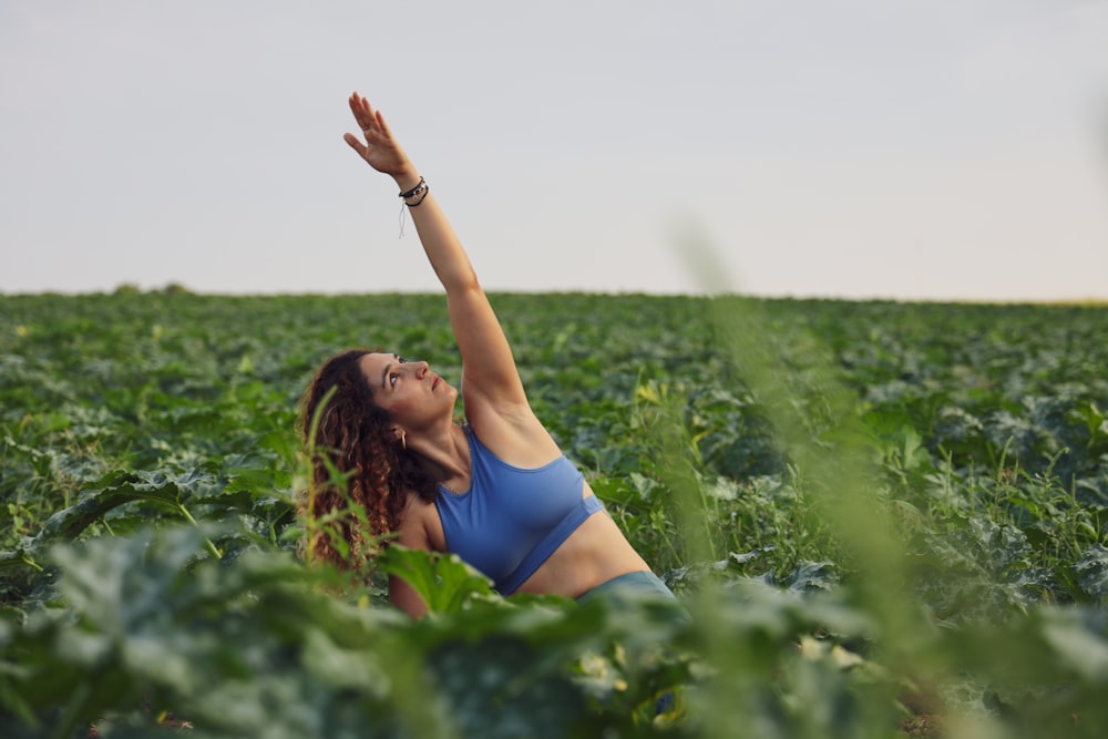 woman sitting on ground while raising her left hand during daytime