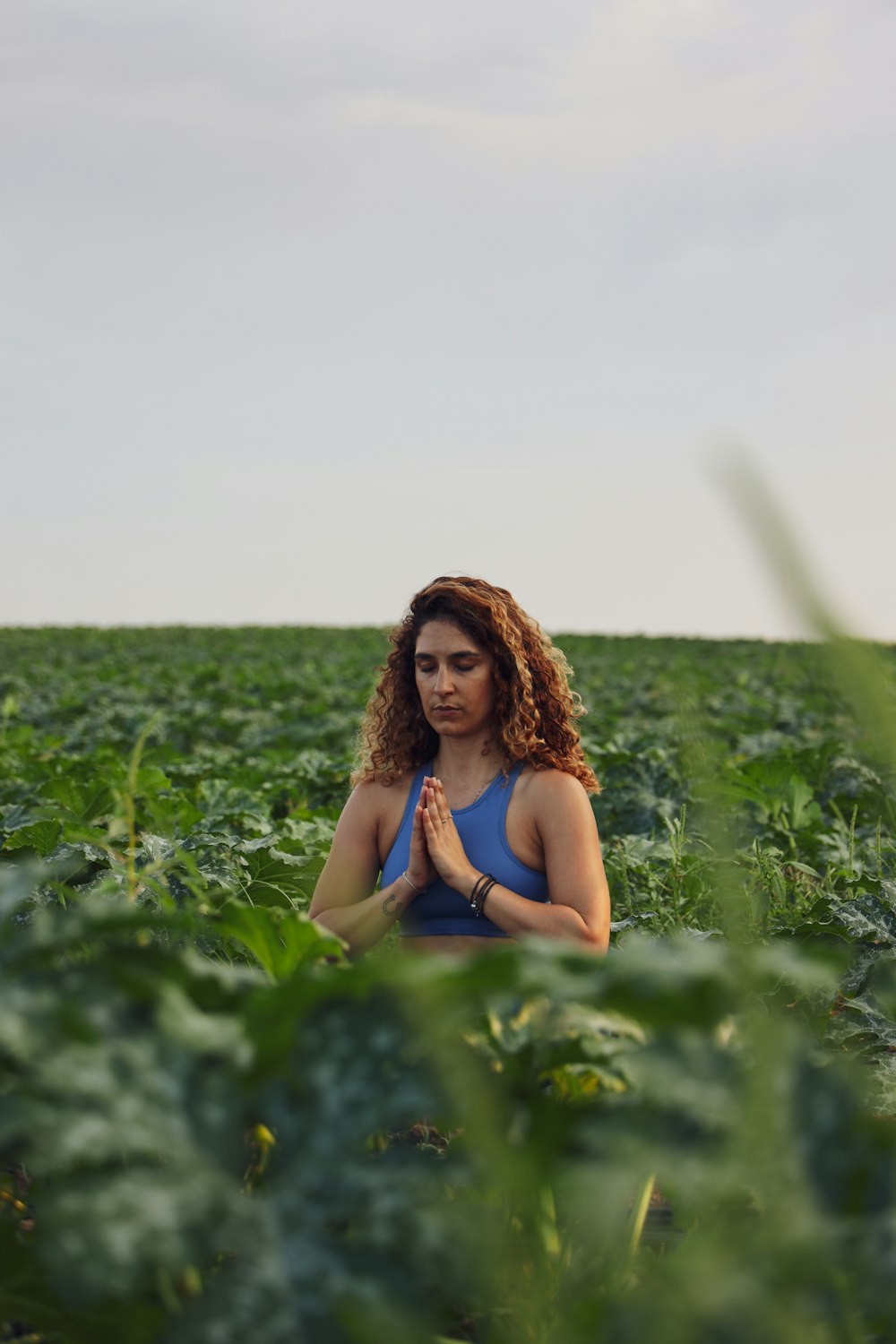 selective focus photography of woman meditating while sitting on ground surrounded by plants