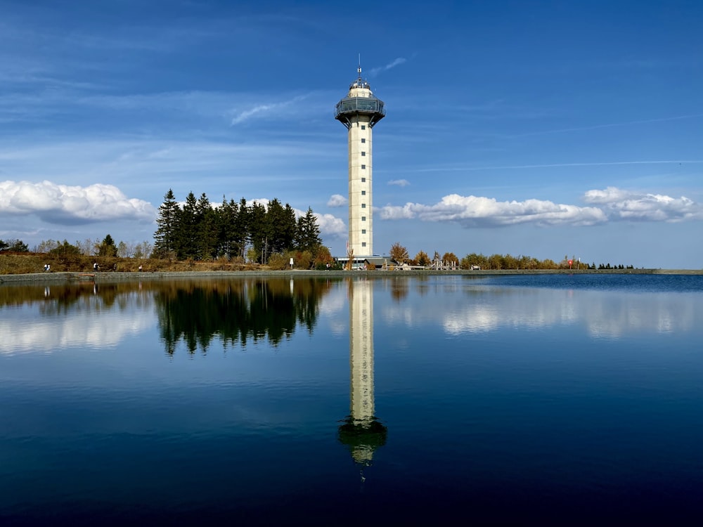 white lighthouse reflection on body of water