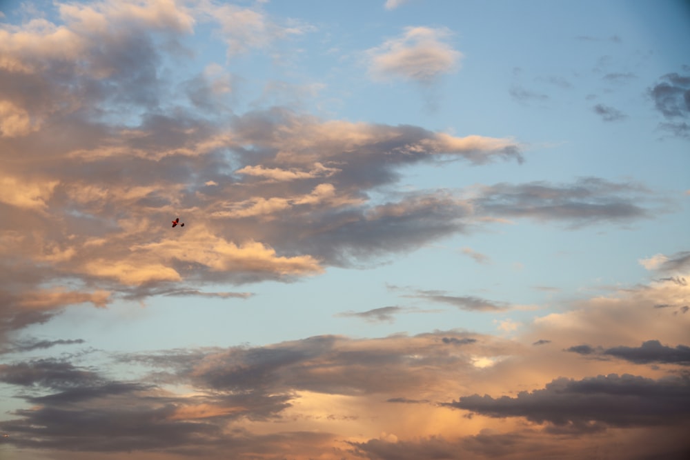 a kite flying through a cloudy blue sky