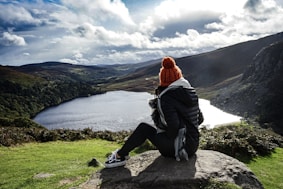 woman wearing black jacket sitting on rock