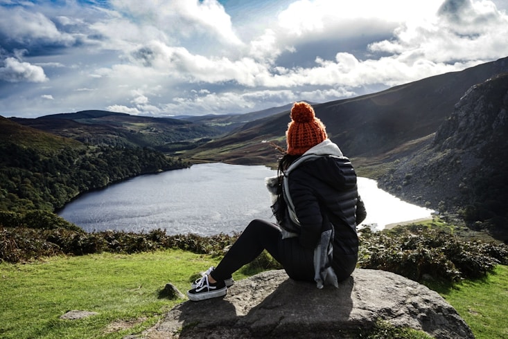 woman wearing black jacket sitting on rock