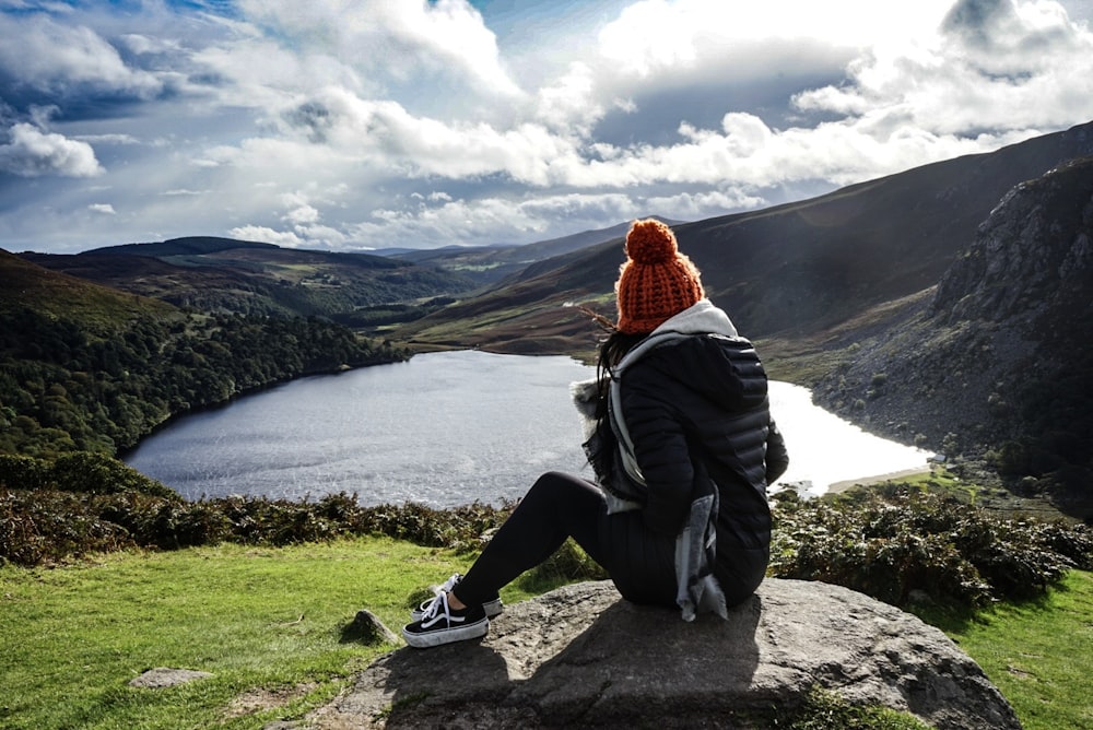 woman wearing black jacket sitting on rock