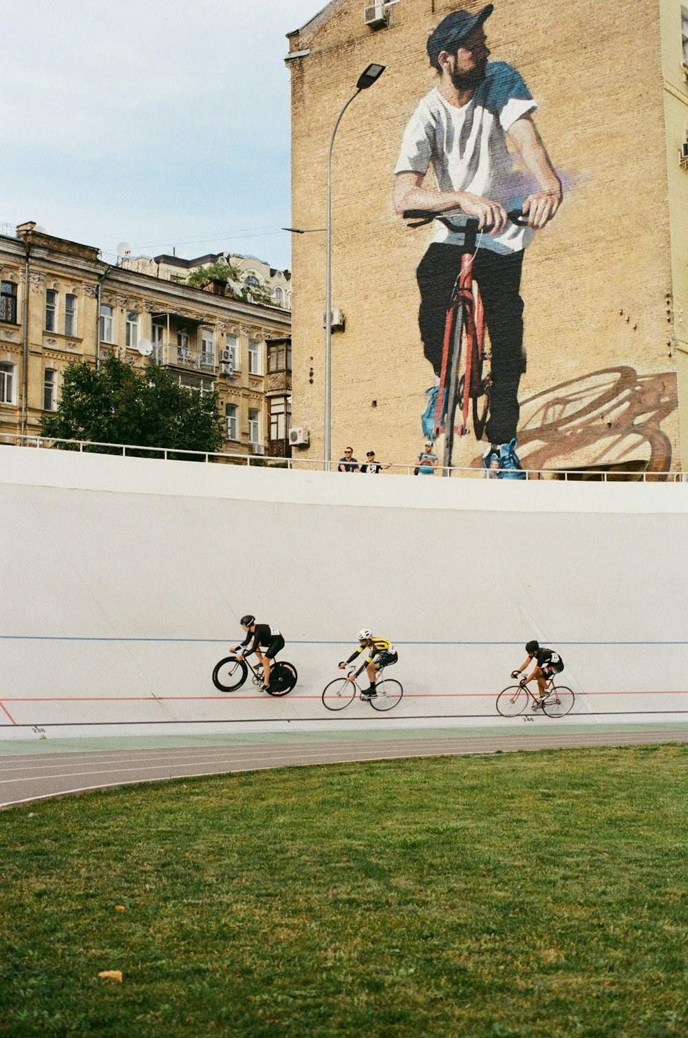 three person riding bike on track mural
