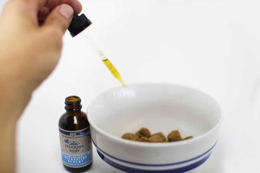 person putting liquid drops in bowl